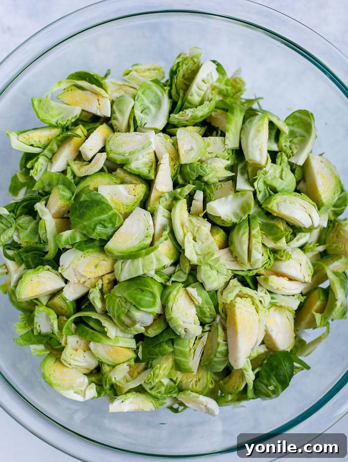 Freshly shredded Brussels sprouts in a clear glass bowl, ready for salad preparation.
