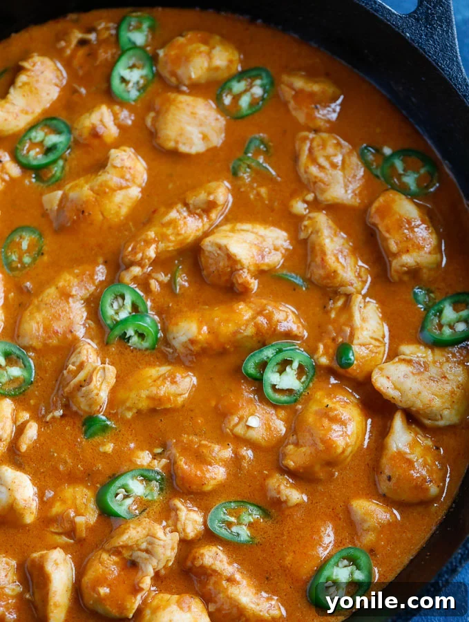 A top-down shot of Thai Red Curry Chicken in a bowl, showing the rich red sauce, tender chicken, and vibrant garnishes.