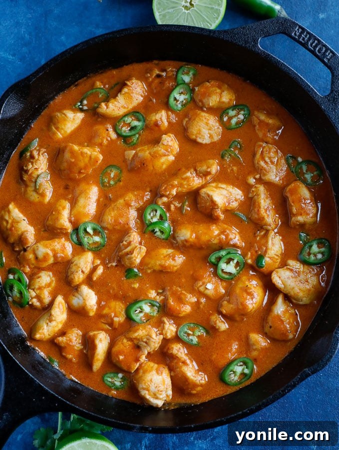 An overhead shot of a table setting featuring a generous bowl of Thai Red Curry Chicken, with rice and fresh lime wedges, ready for a comforting meal.