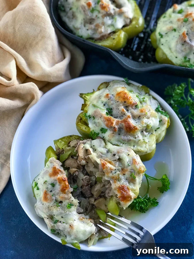 A small white plate with a Philly Cheesesteak Stuffed Bell pepper on a blue counter, ready to be enjoyed.