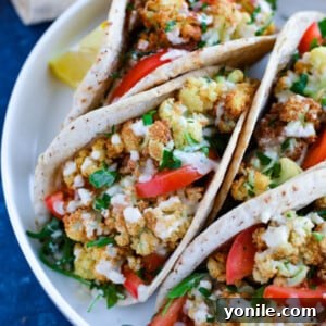 A beautifully plated Vegetarian Cauliflower Pita Wrap, showcasing its roasted cauliflower, fresh vegetables, and creamy tahini dressing.
