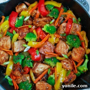 Teriyaki Salmon Stir Fry in a large nonstick skillet, garnished with sesame seeds and green onions.