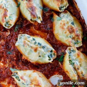 A baking dish with spinach artichoke stuffed shells in tomato basil marinara sauce.