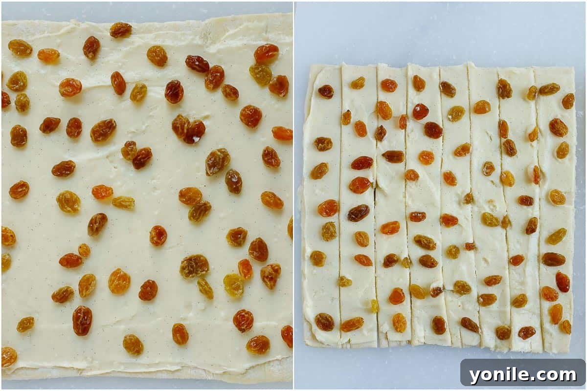 A puff pastry sheet covered with crème patissiere and raisins, being cut into even 1-inch strips.