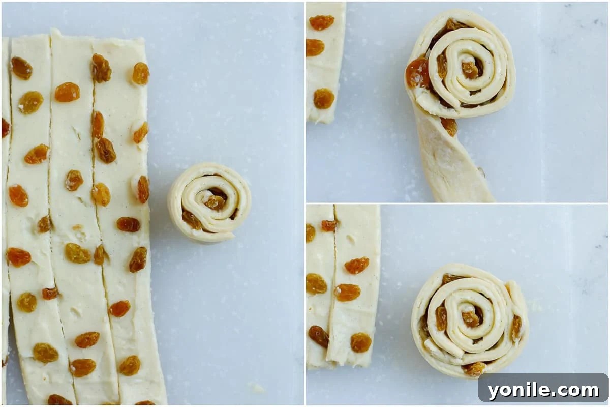 A hand demonstrating the process of rolling two pastry strips together to form a Pain Aux Raisins spiral.