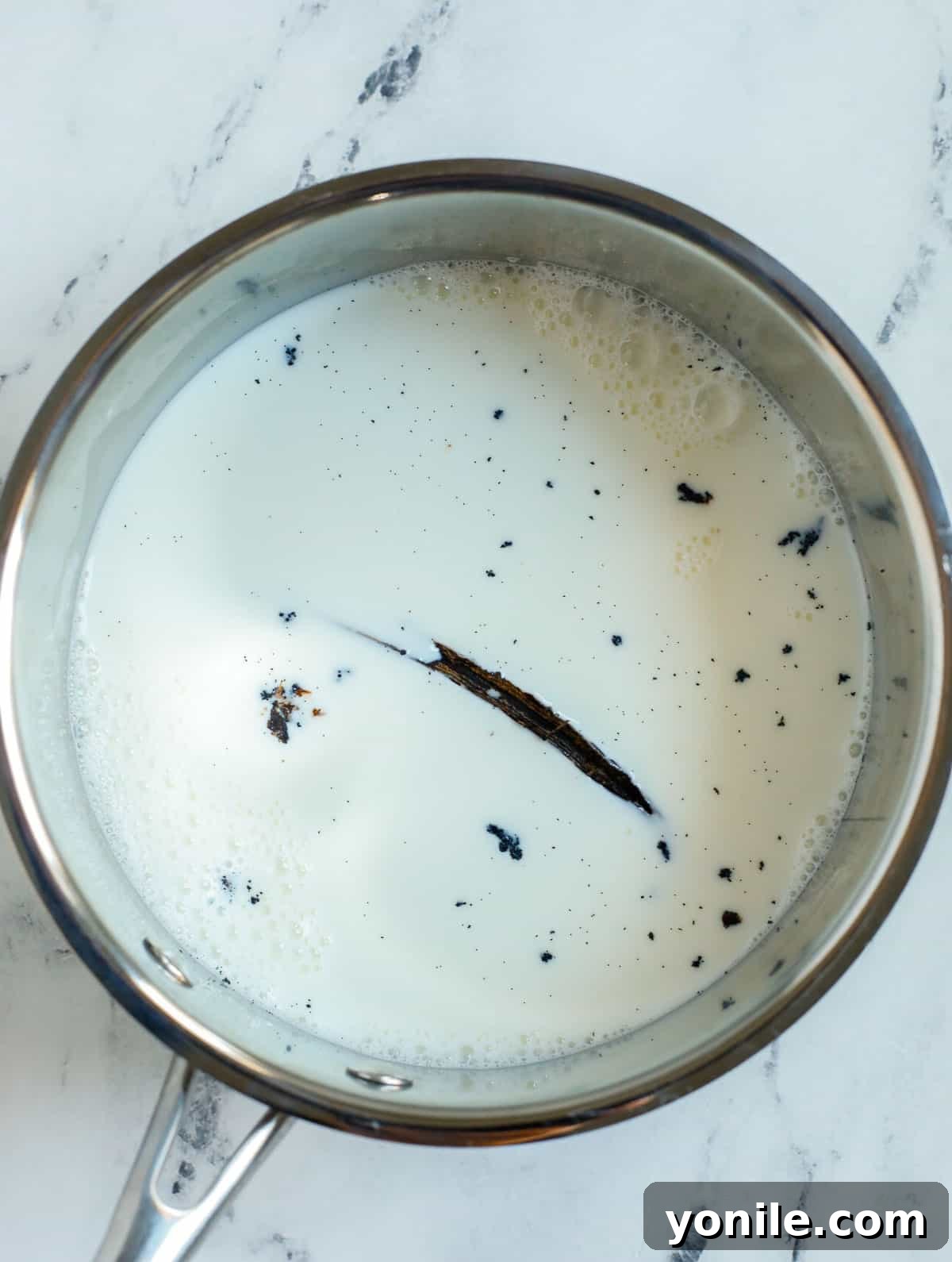 Milk gently simmering in a pot with a vanilla bean pod, infusing its aroma.