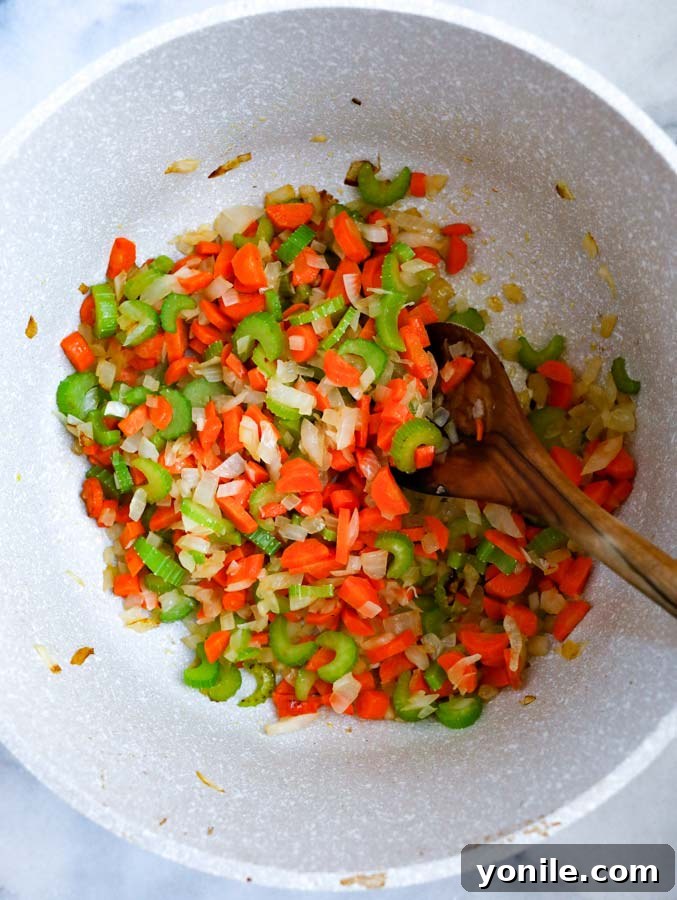 Zesty Lemon Chicken Orzo Delight 3 Close-up of sautéed onions, carrots, and celery in a pot, ready for the next step.