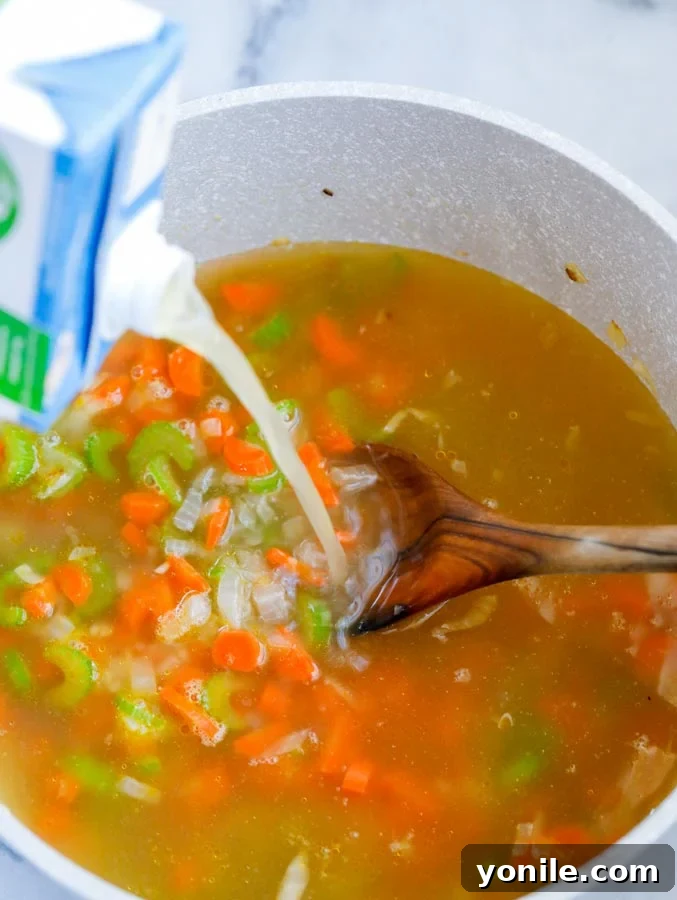 Zesty Lemon Chicken Orzo Delight 4 Top down shot of chicken broth being added to a pot of diced vegetables.