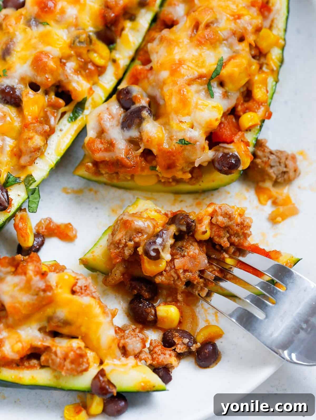 A fork taking a bite from a perfectly cooked zucchini boat, showcasing the rich filling