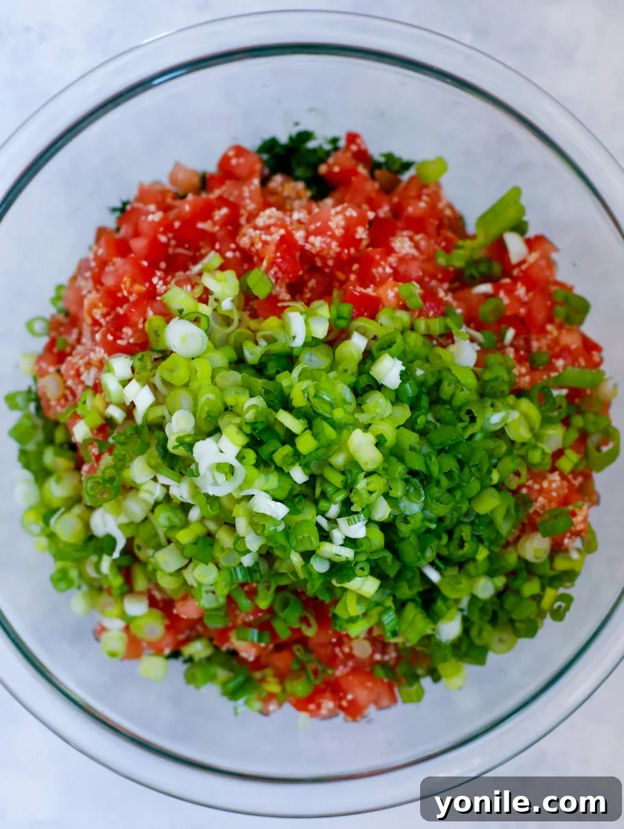 The tabbouleh salad ingredients freshly mixed in a glass bowl