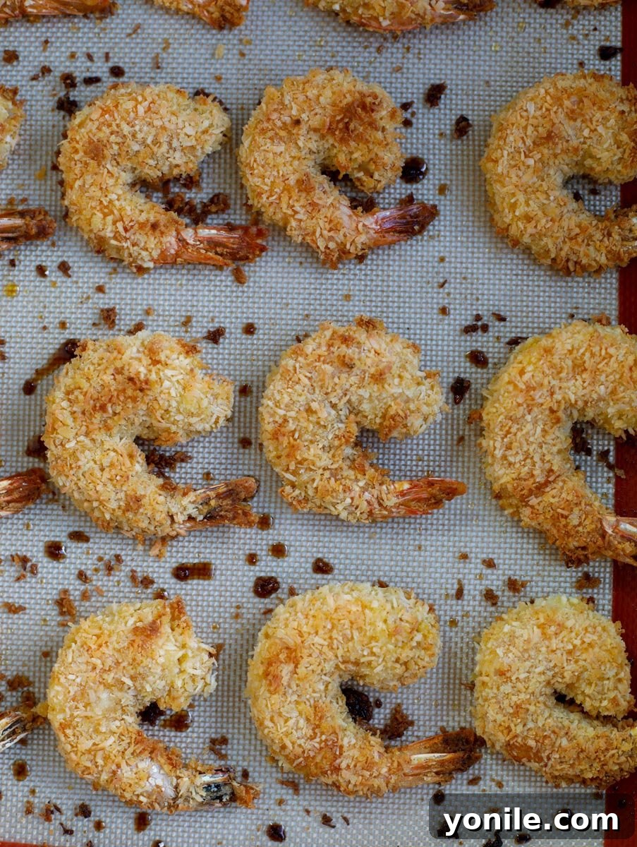The cooked coconut shrimp on a baking sheet