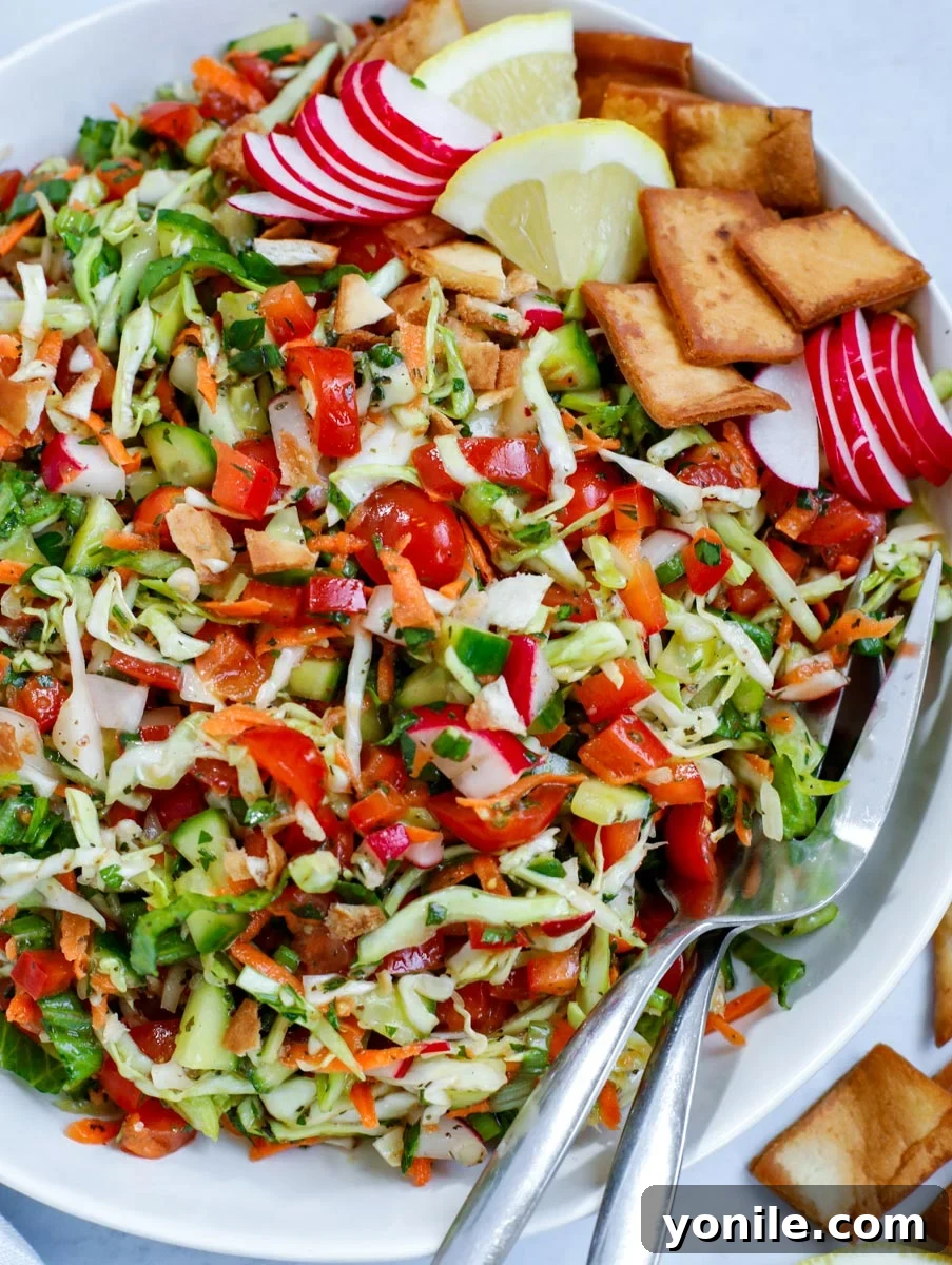 Cabbage fattoush salad in a bowl with serving spoons