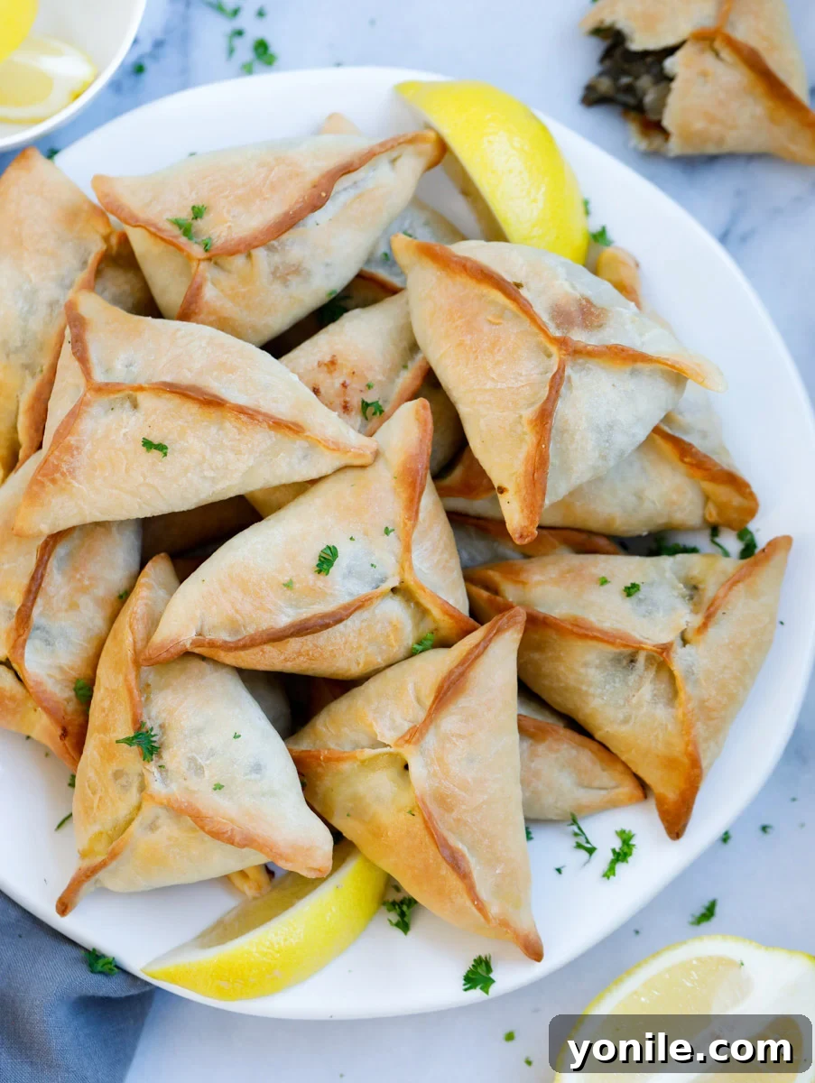 Traditional Lebanese Spinach Pies 2 Lebanese Spinach Pie served on a plate with lemon wedges and garnished with parsley