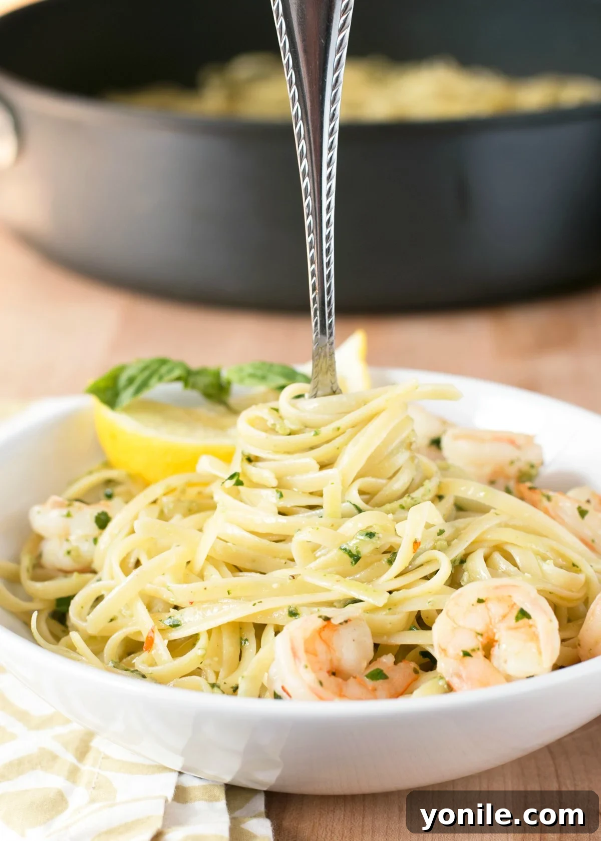 Vibrant Pesto Shrimp Scampi Pasta 3 Large white bowl of pesto shrimp scampi pasta with a fork in the center, ready to be served.