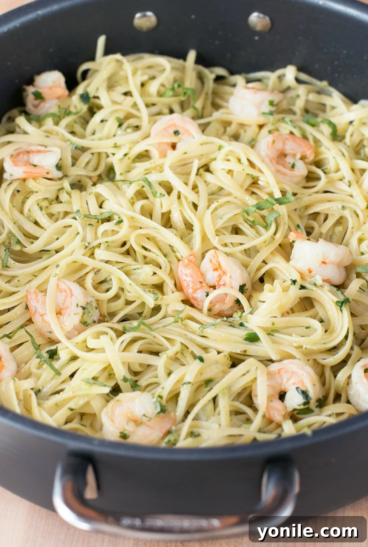 Vibrant Pesto Shrimp Scampi Pasta 5 Pesto shrimp scampi with pasta being tossed together in a large stockpot, showcasing the rich green sauce.
