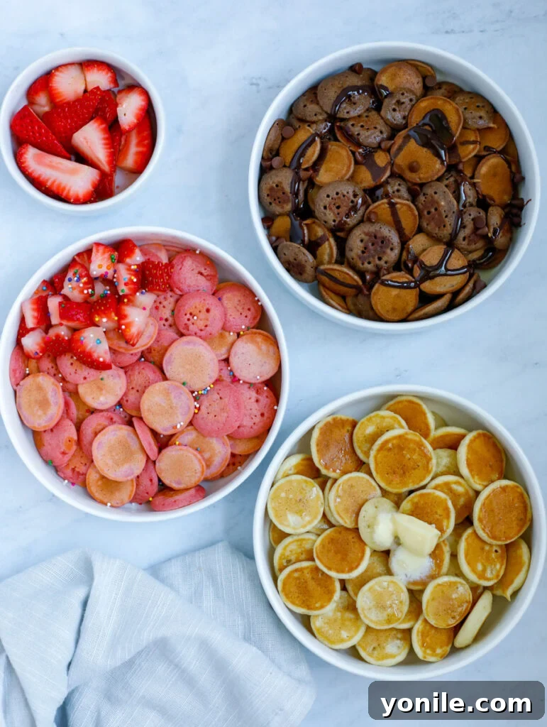 A vibrant photo showcasing three different flavors of mini pancake cereal: classic, chocolate, and strawberry.