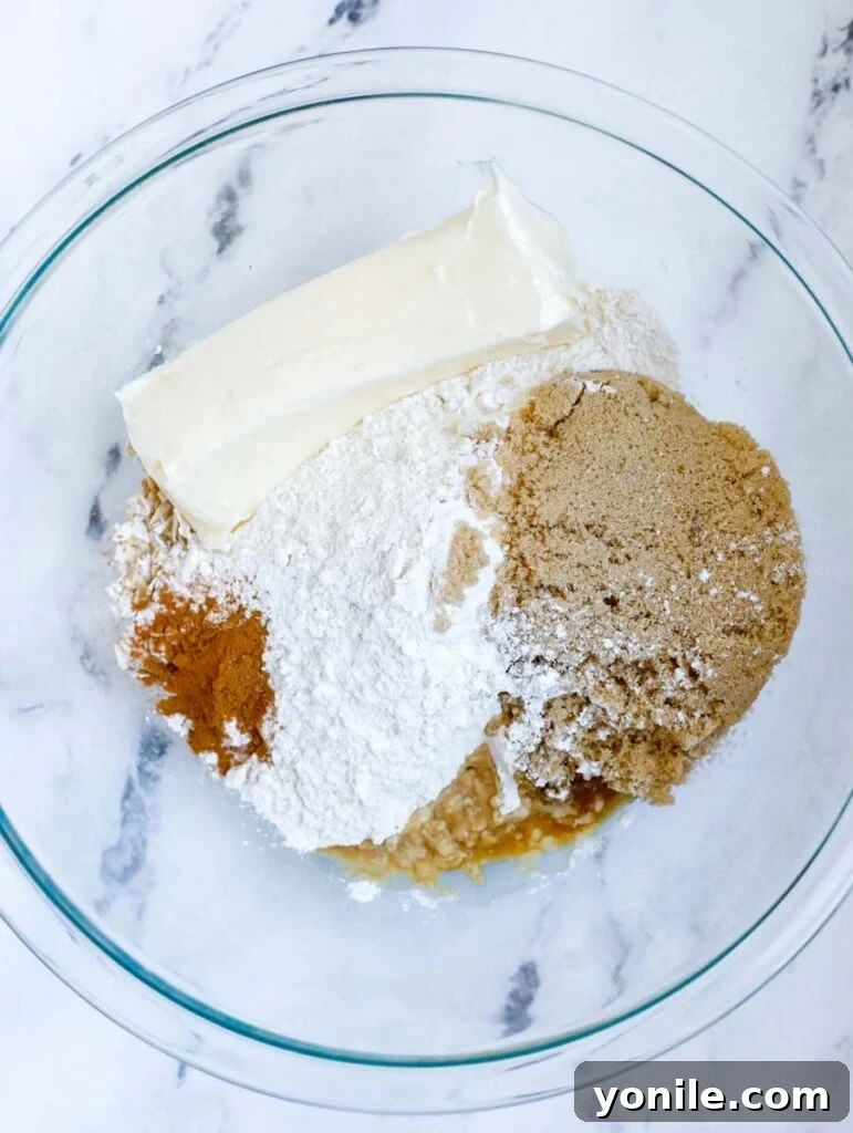 Crisp ingredients in a bowl, with soft butter being worked into the dry mixture to form crumbs.
