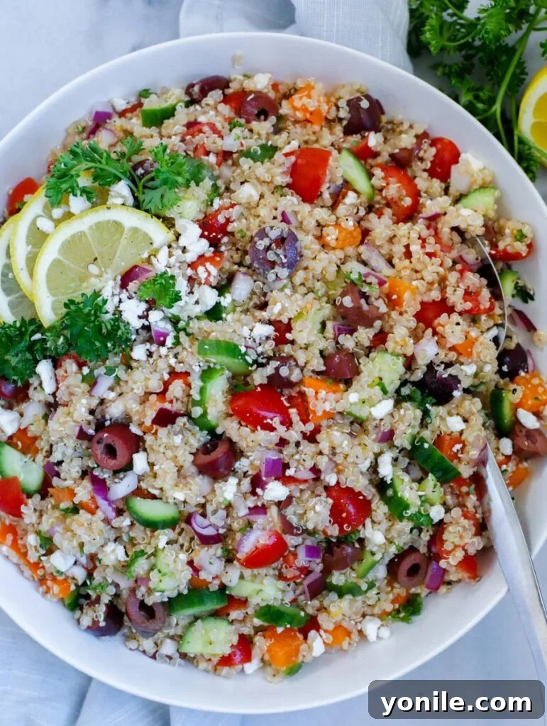 mediterranean quinoa salad served in a dish, topped with crumbled feta cheese and lemon wedges for garnish