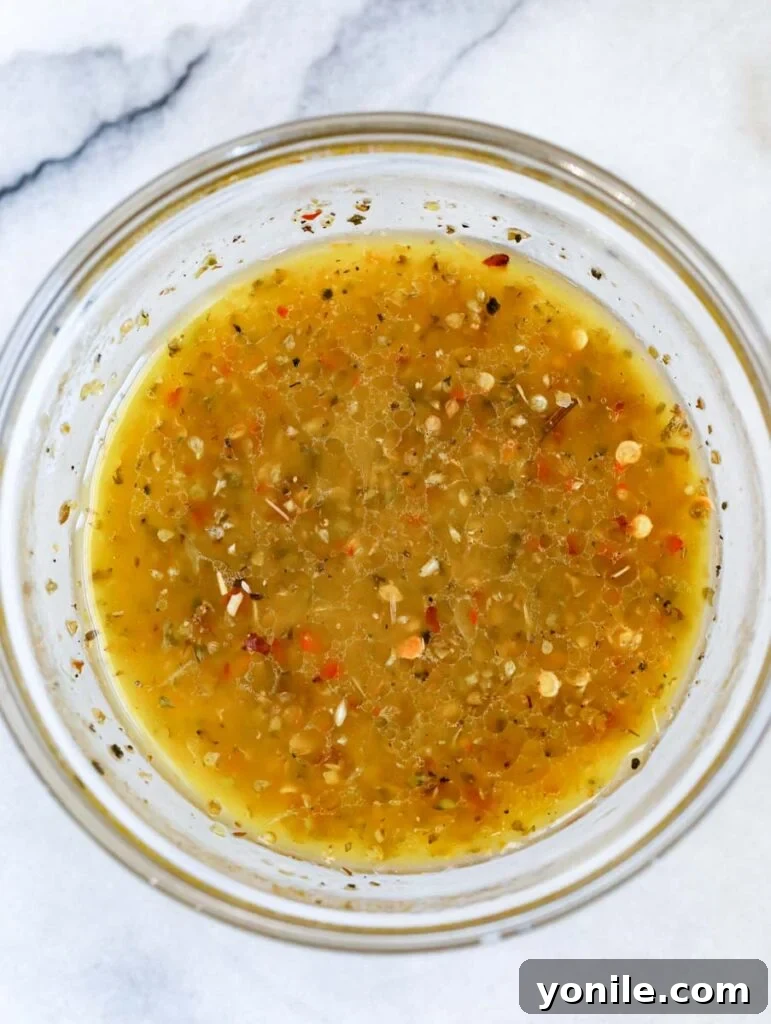 a vibrant Mediterranean dressing in a clear glass bowl, garnished with herbs