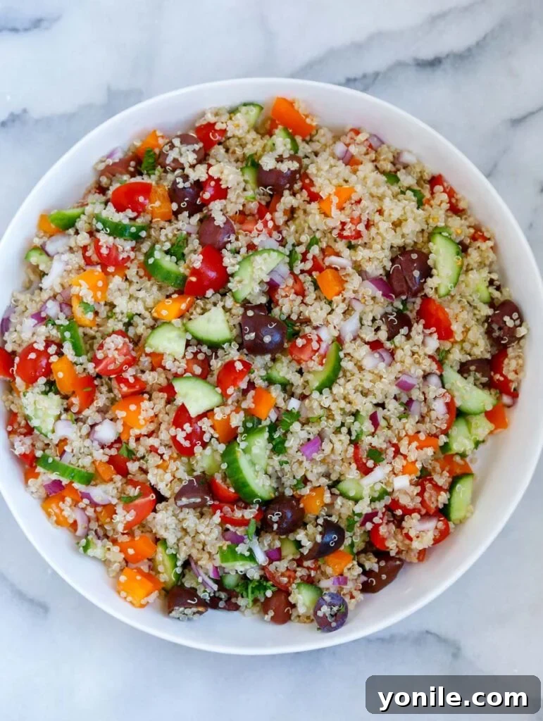 all the fresh ingredients for the Mediterranean quinoa salad mixed together in a large bowl