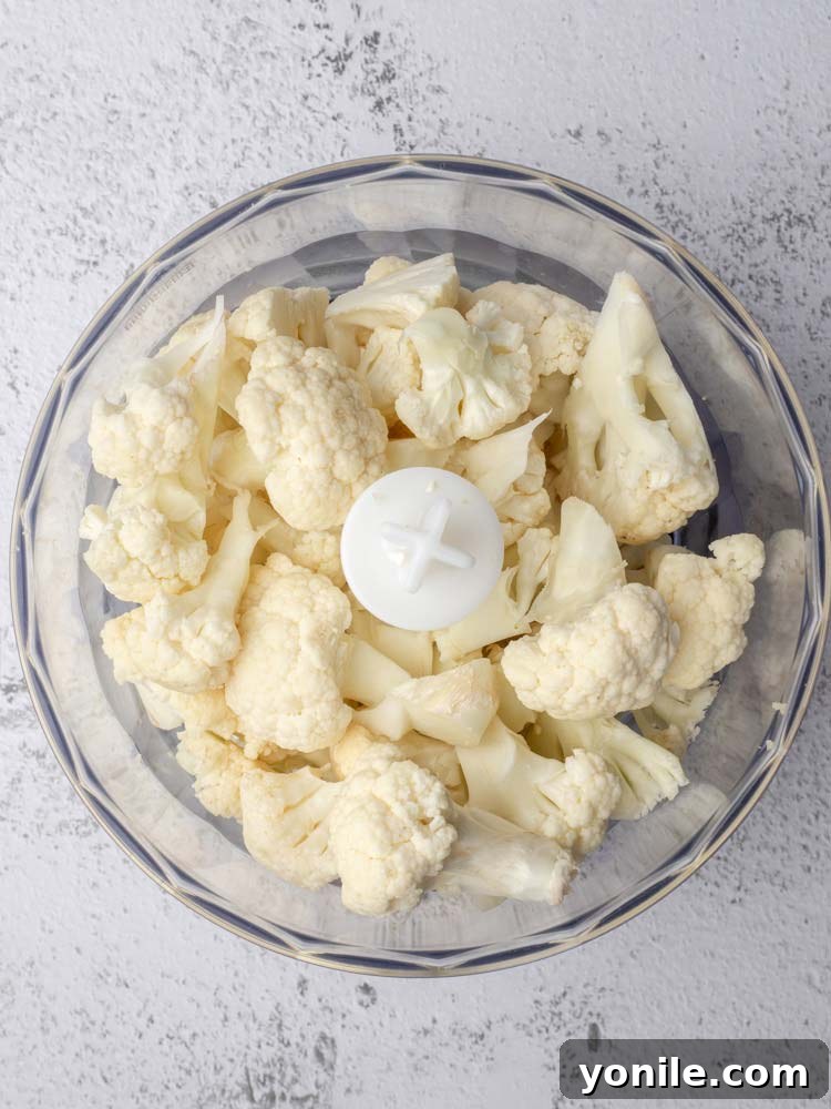 Cauliflower florets placed inside a food processor bowl