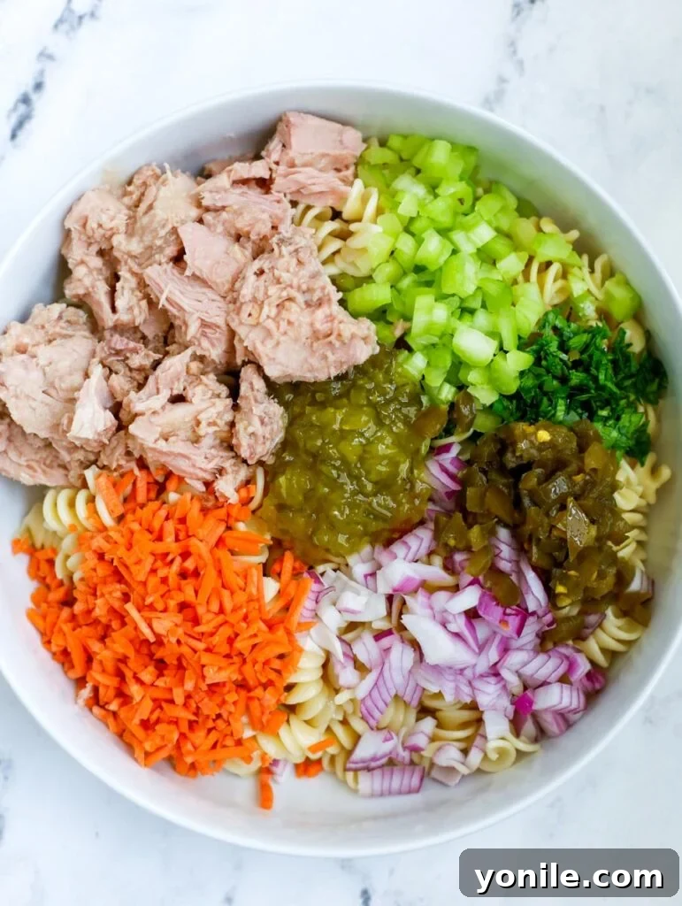 Cooked pasta and mixed vegetables in a white bowl, ready for the dressing.