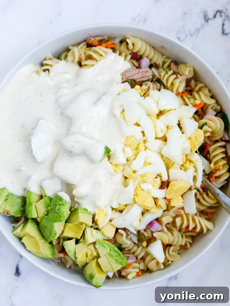 The creamy dressing generously poured over the tuna pasta salad, ready for a final toss.