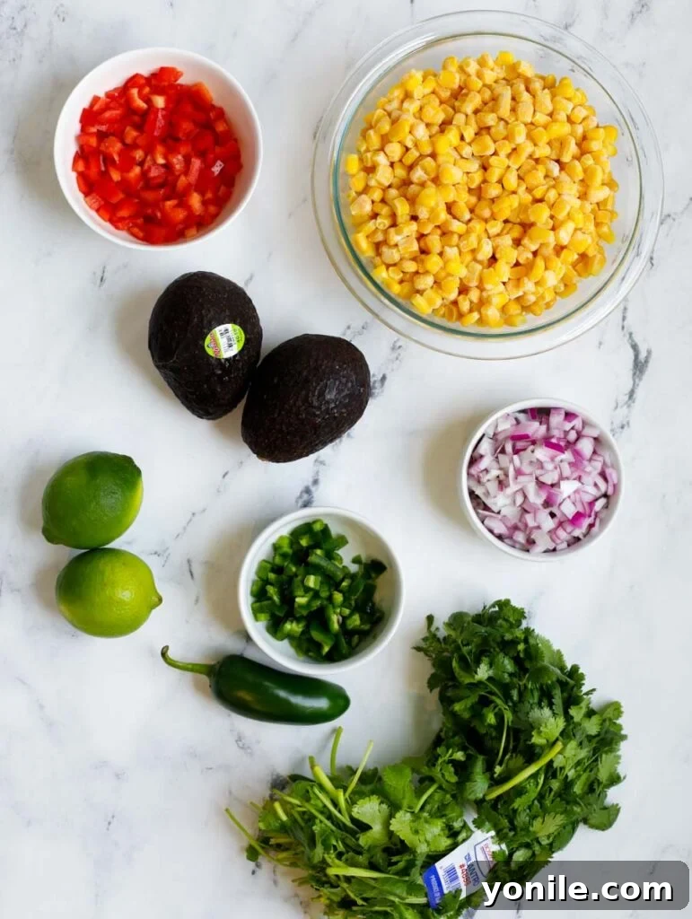 Close-up shot of fresh ingredients for Mexican Street Corn Salad, including corn, bell peppers, avocados, onion, and cilantro.