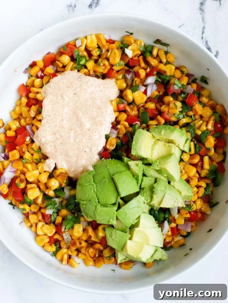 Close-up of Mexican street corn salad showing the creamy dressing, avocado, and corn kernels.