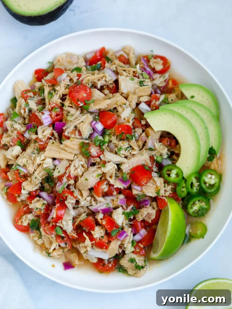 A vibrant top-down shot of a bowl of Tuna Ceviche, garnished with fresh herbs and lime wedges, ready to be served.