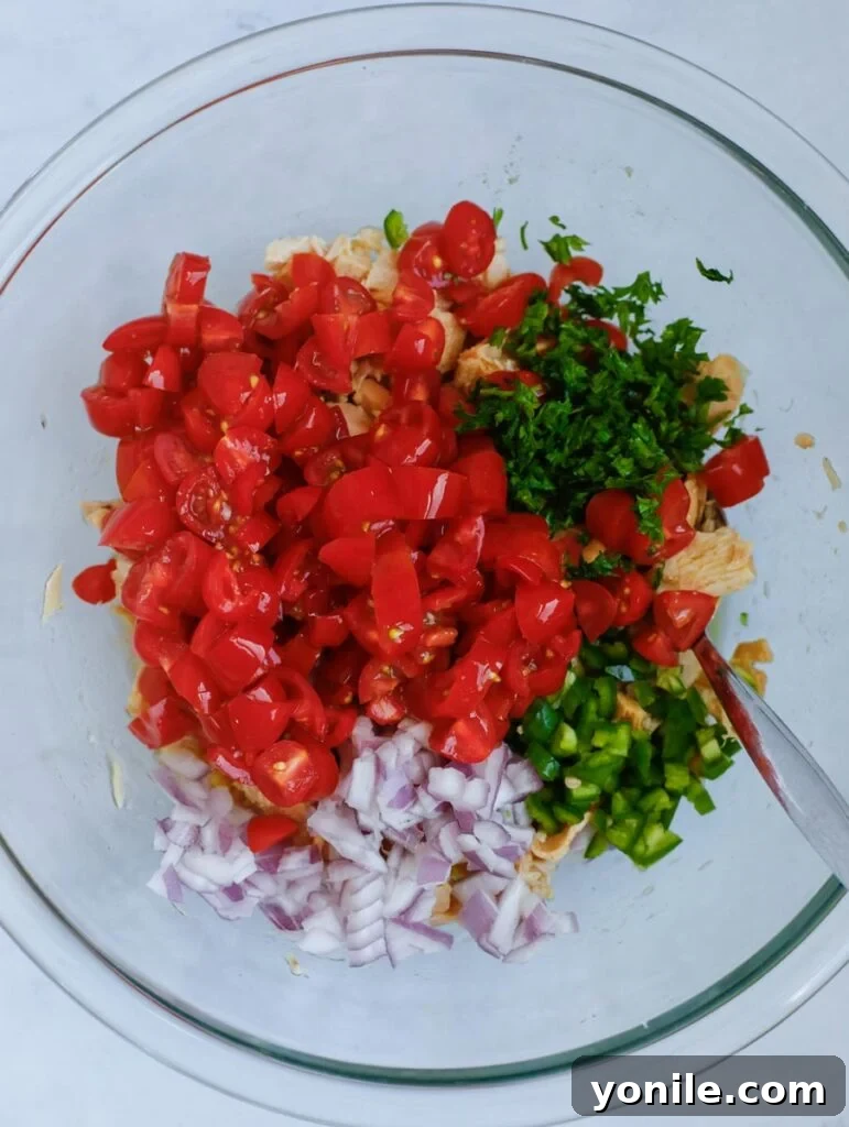 A bowl showing chunk tuna mixed with lime juice, olive oil, salt, and cumin powder, marinating together.