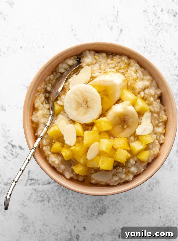 Perfect Oatmeal Every Time 10 cooked oatmeal in a bowl topped with some pineapple, banana and honey