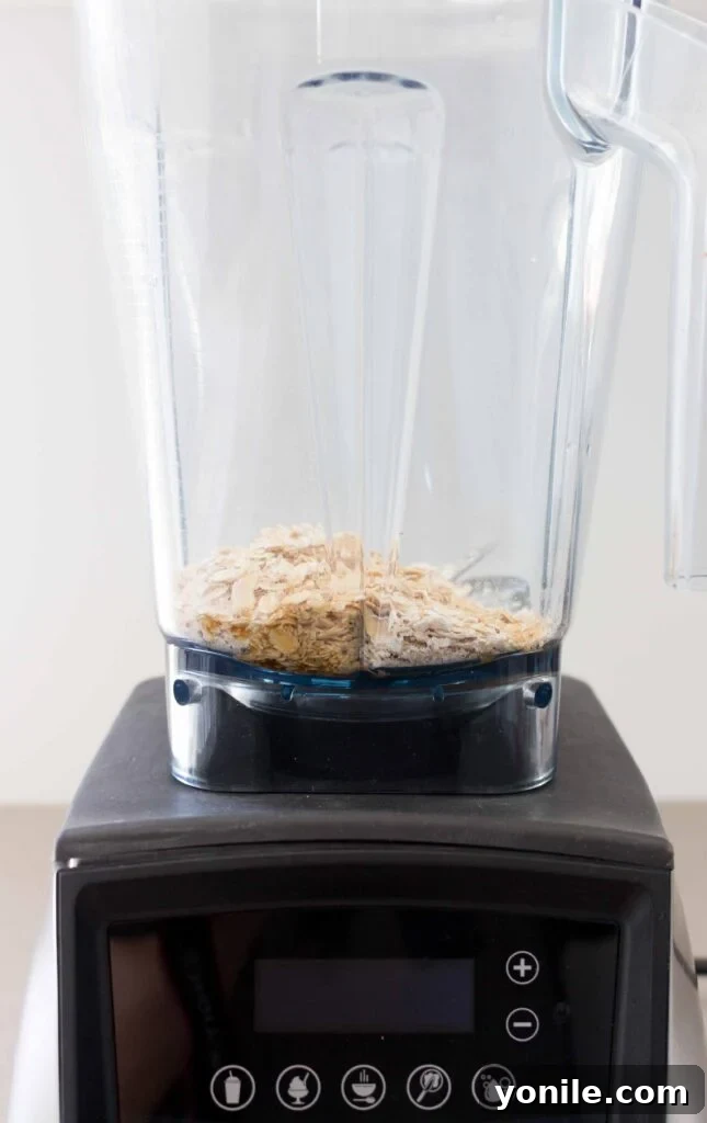 Rolled oats being added into a blender jug, ready for making oat milk