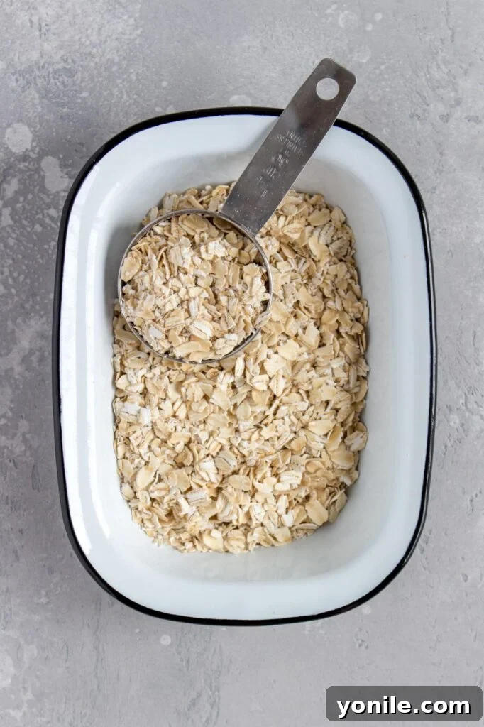 A bowl of whole rolled oats sits next to a blender, ready to be transformed into flour.
