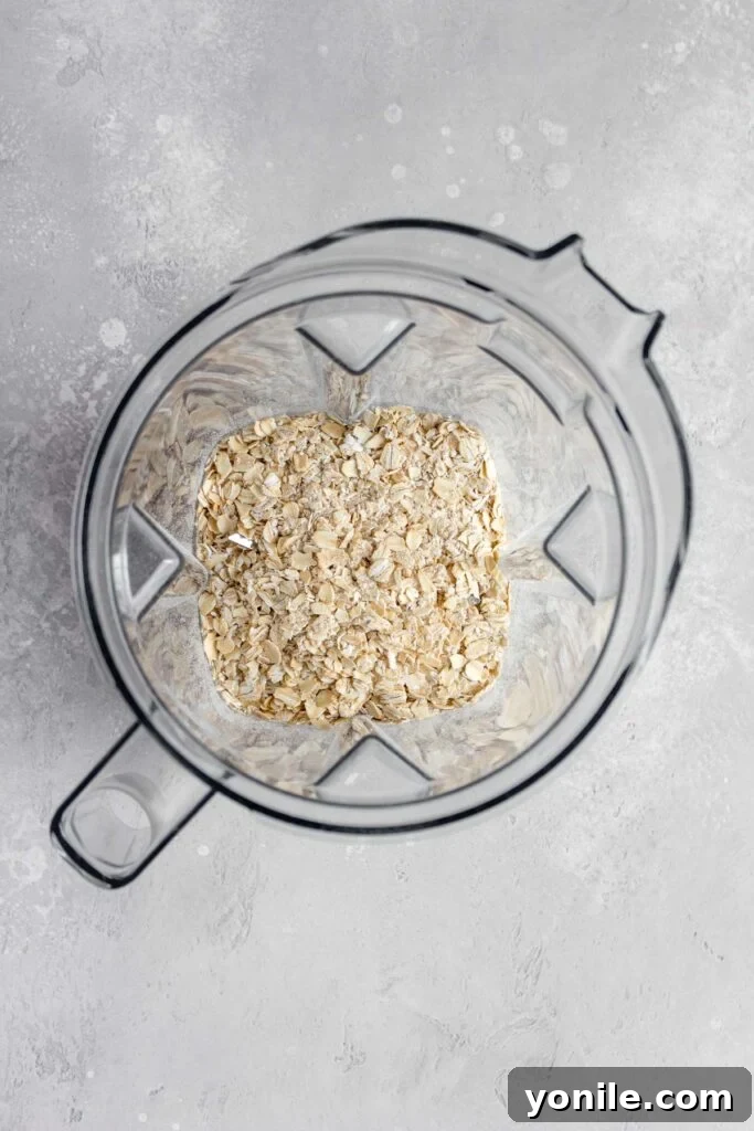 Rolled oats are poured into a blender jar, ready for grinding.