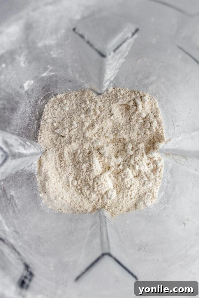 The blender is actively grinding oats, transforming them into fine flour.