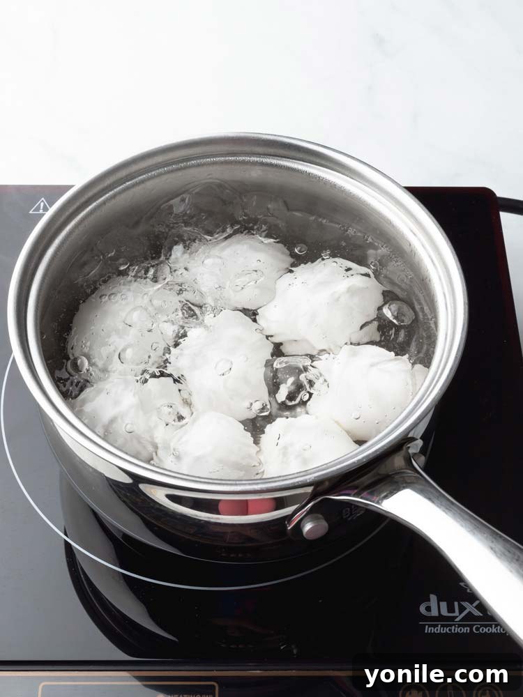 Eggs being carefully lowered into a pot of simmering water.