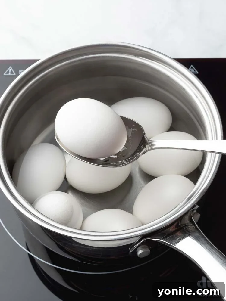 An egg being carefully lifted out of the simmering pot with a slotted spoon.