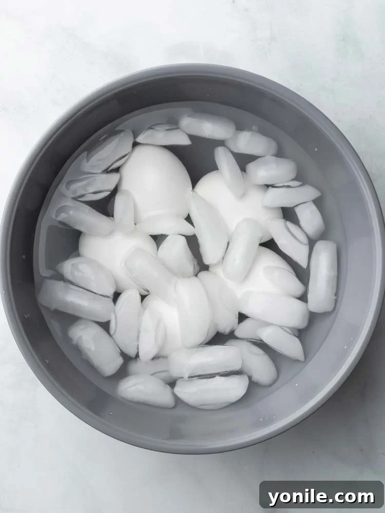 Cooked eggs submerged in an ice water bath.