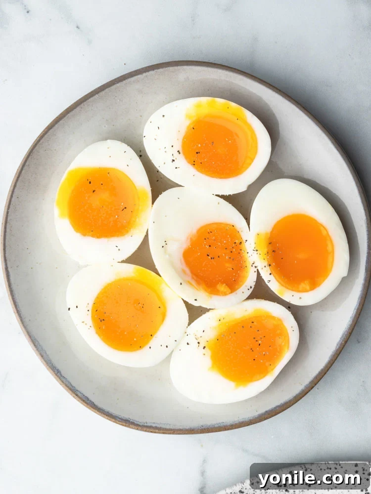 Mastering the Soft Boiled Egg 3 A plate featuring two soft-boiled eggs, cut open to reveal their luscious, runny yolks, surrounded by fresh herbs.