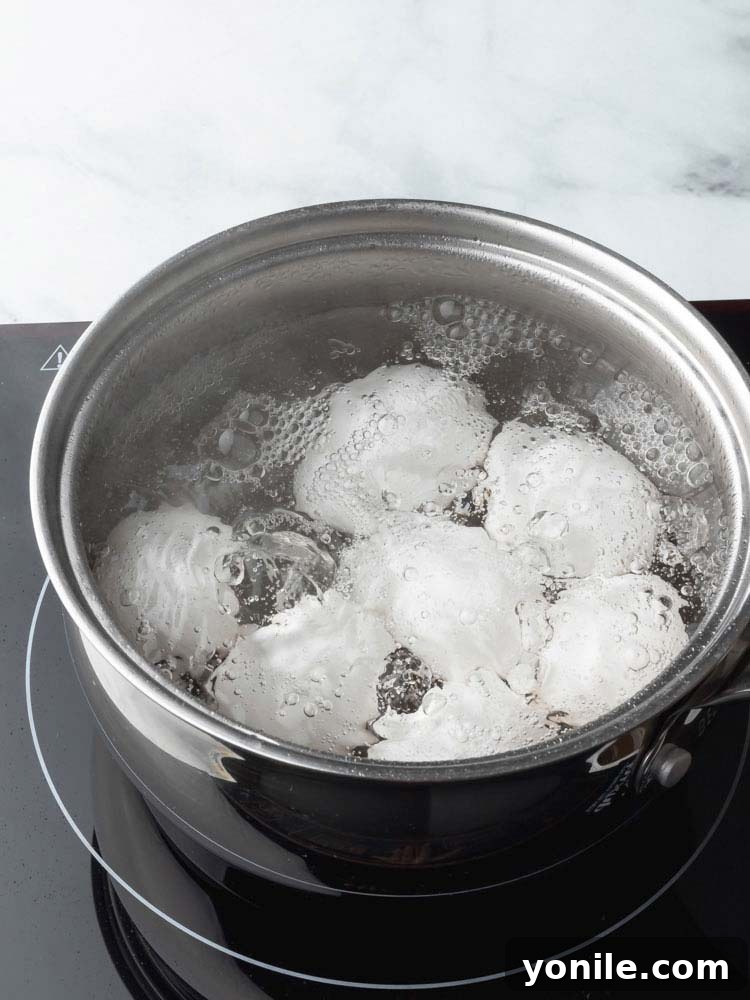 Mastering the Soft Boiled Egg 4 Eggs simmering gently in a pot of water on the stove, steam rising.