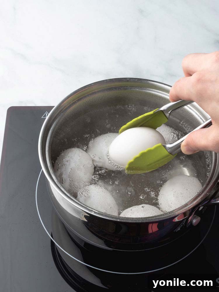Mastering the Soft Boiled Egg 5 An egg being carefully lowered into simmering water using a slotted spoon, highlighting gentle handling.