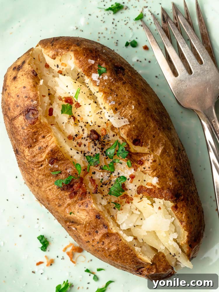 baked potato on a plate topped with bacon, parsley and black pepper