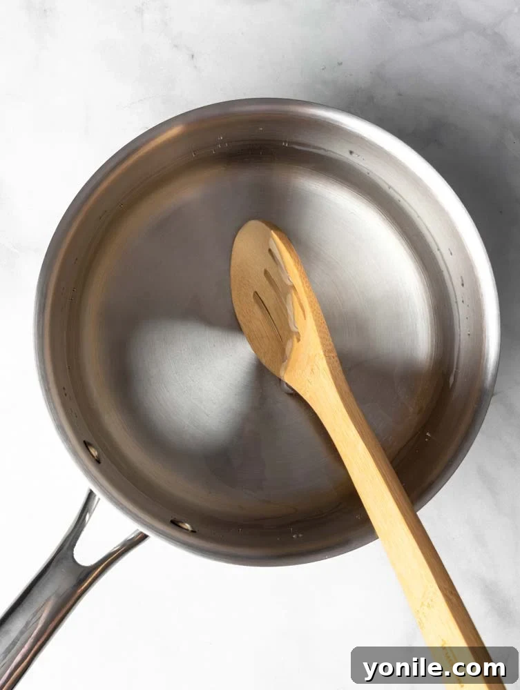 Mastering the Poached Egg 4 A pot of hot water with a spoon creating a gentle swirl, demonstrating the start of the whirlpool method for poaching eggs.