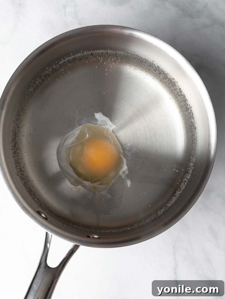 Mastering the Poached Egg 6 A poached egg cooking in simmering water, its whites gently set around the yolk.
