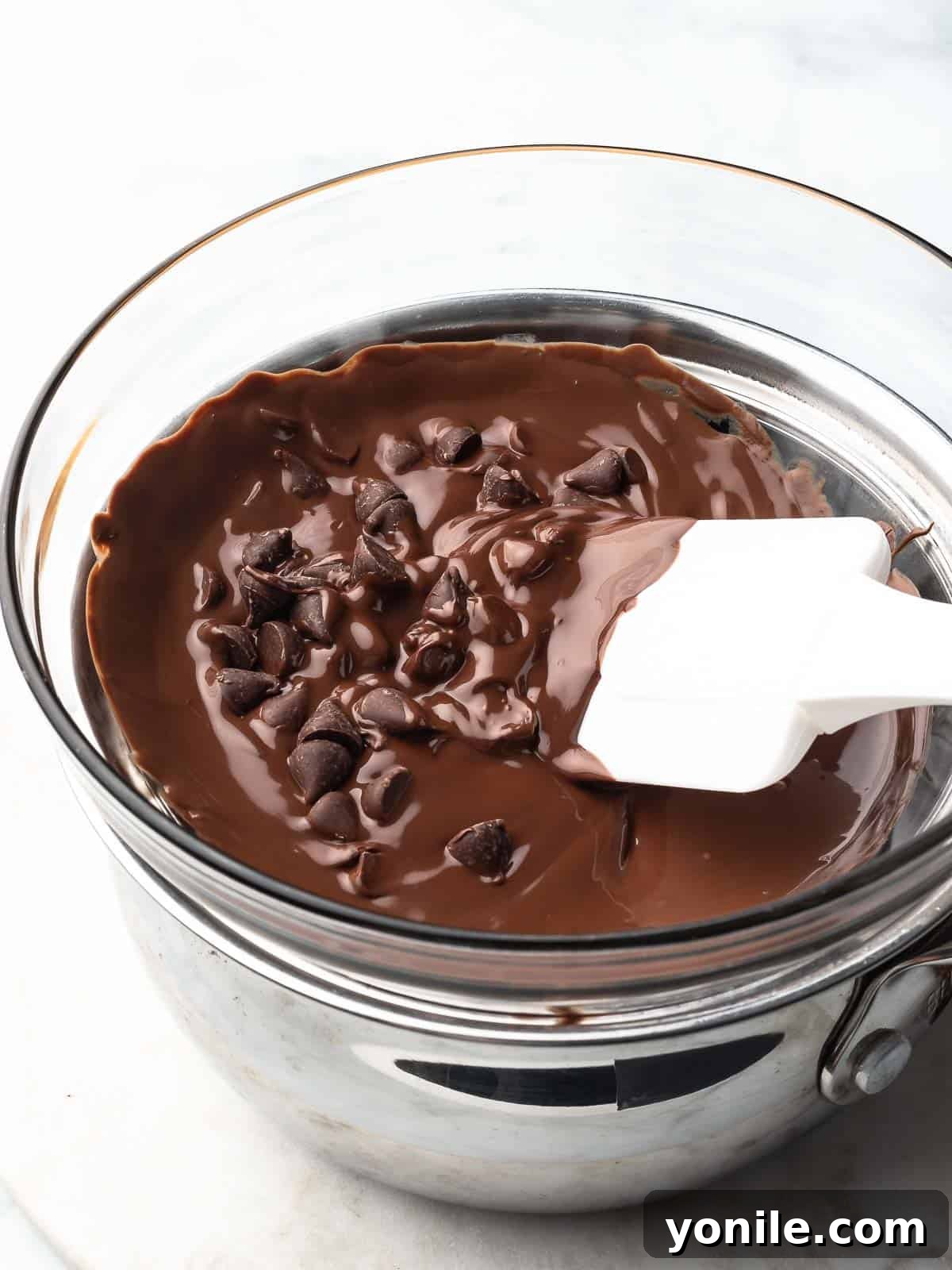 Mastering Chocolate Melting 4 Chocolate pieces gently melting in a double boiler over simmering water.