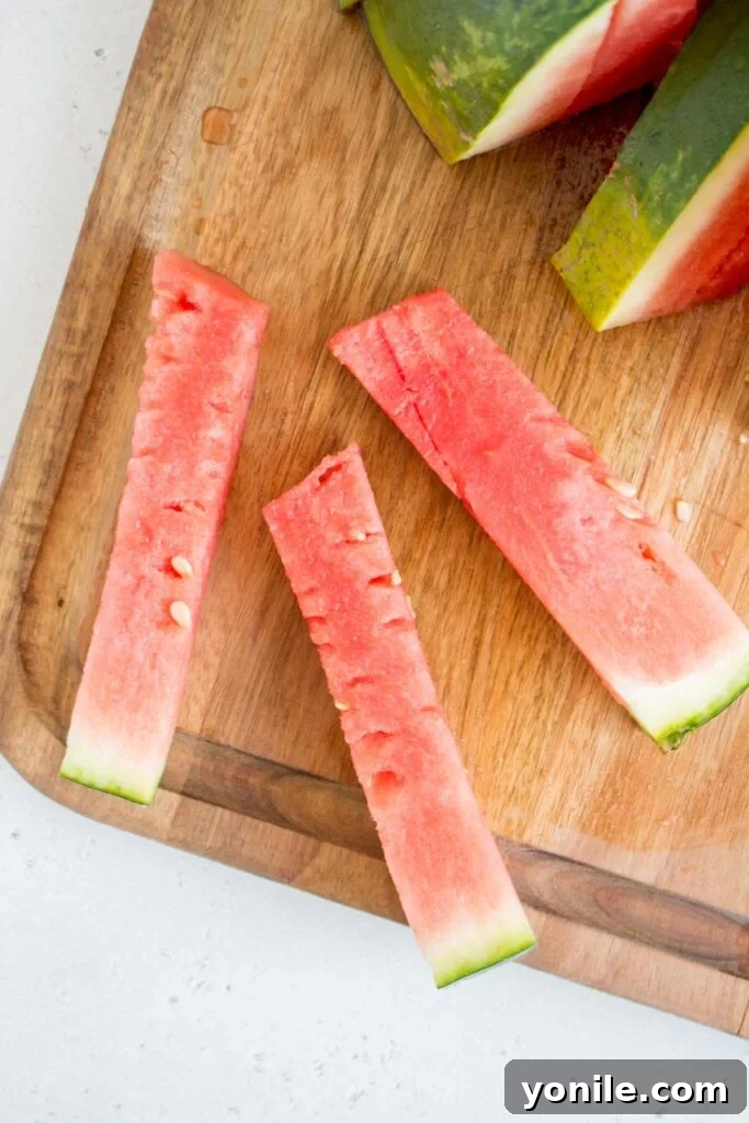 Slice Watermelon Like a Pro 11 Watermelon flesh being carefully removed from the rind after being scored into a grid.