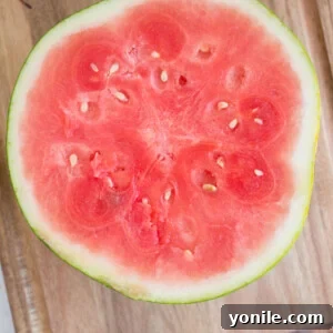 Watermelon cut in half on a cutting board, illustrating the first step in preparation.