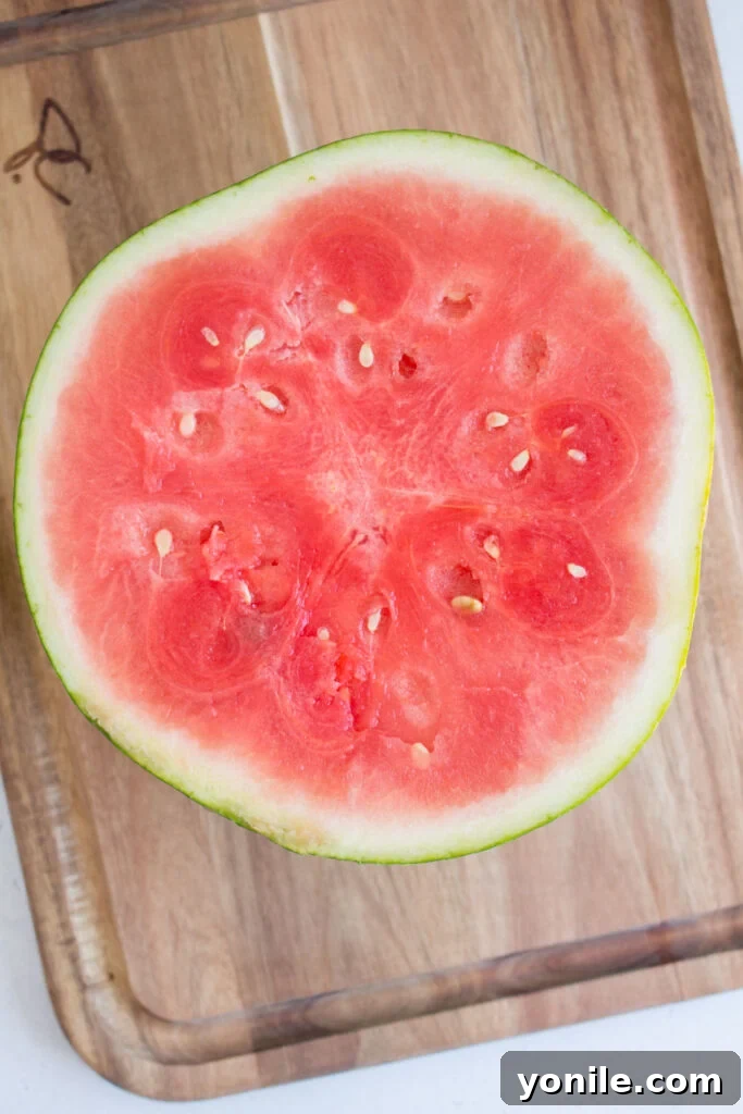 Slice Watermelon Like a Pro 4 A whole watermelon cut cleanly in half, revealing the red flesh inside.