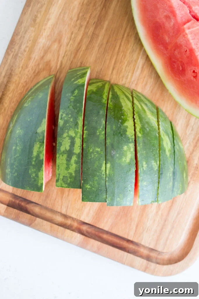Slice Watermelon Like a Pro 6 One quarter of a watermelon being sliced into triangular wedges on a cutting board.